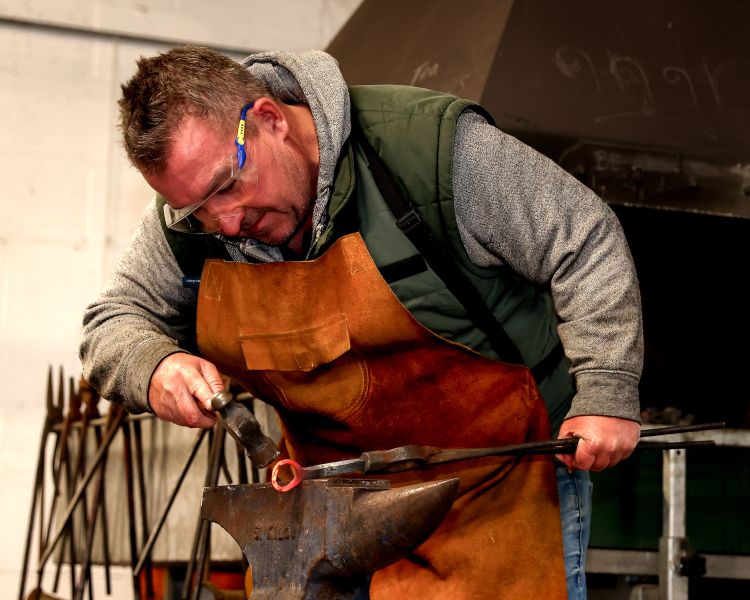 man shaping a bottle opener on a blacksmith day experience