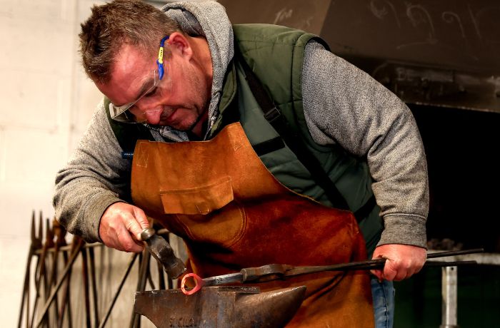 man shaping a bottle opener on a blacksmith day experience