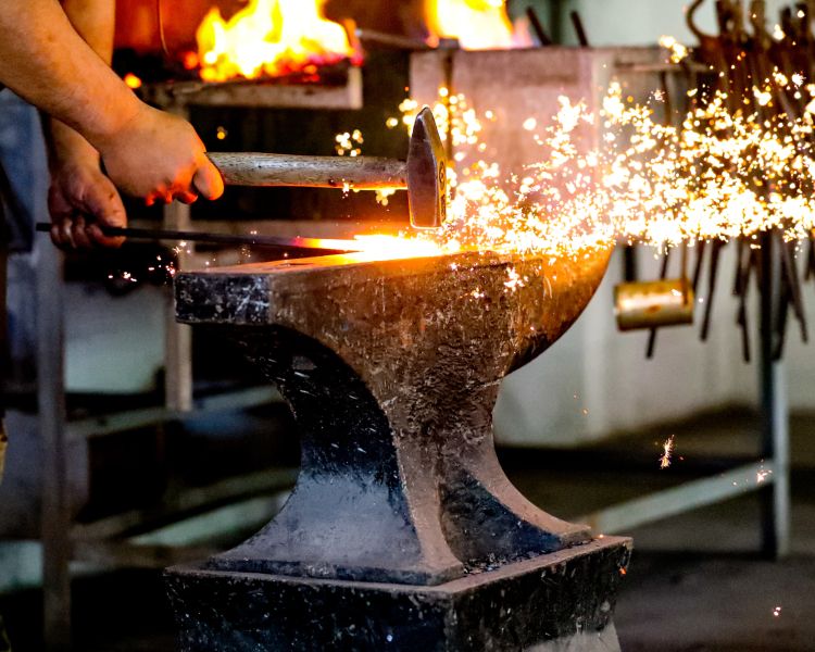 sparks from hot metal being hammered into shape on a blacksmith day experience