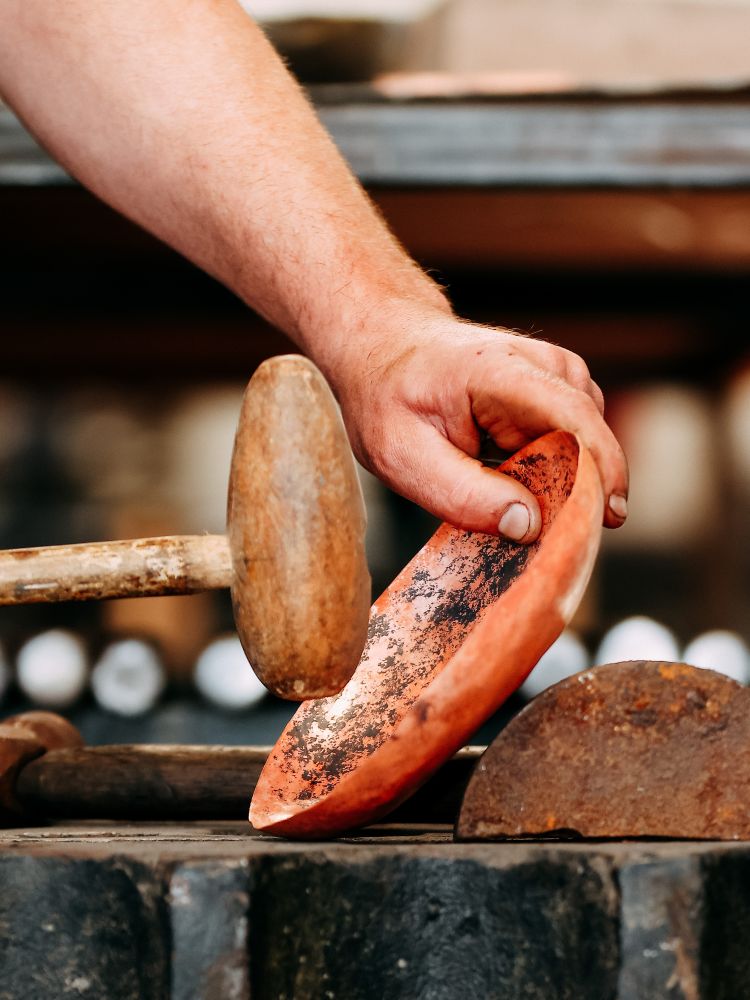 hammering a copper bowl on a silversmith experience