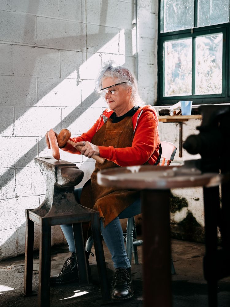 woman hammering a copper bowl into shape on a silversmith day course