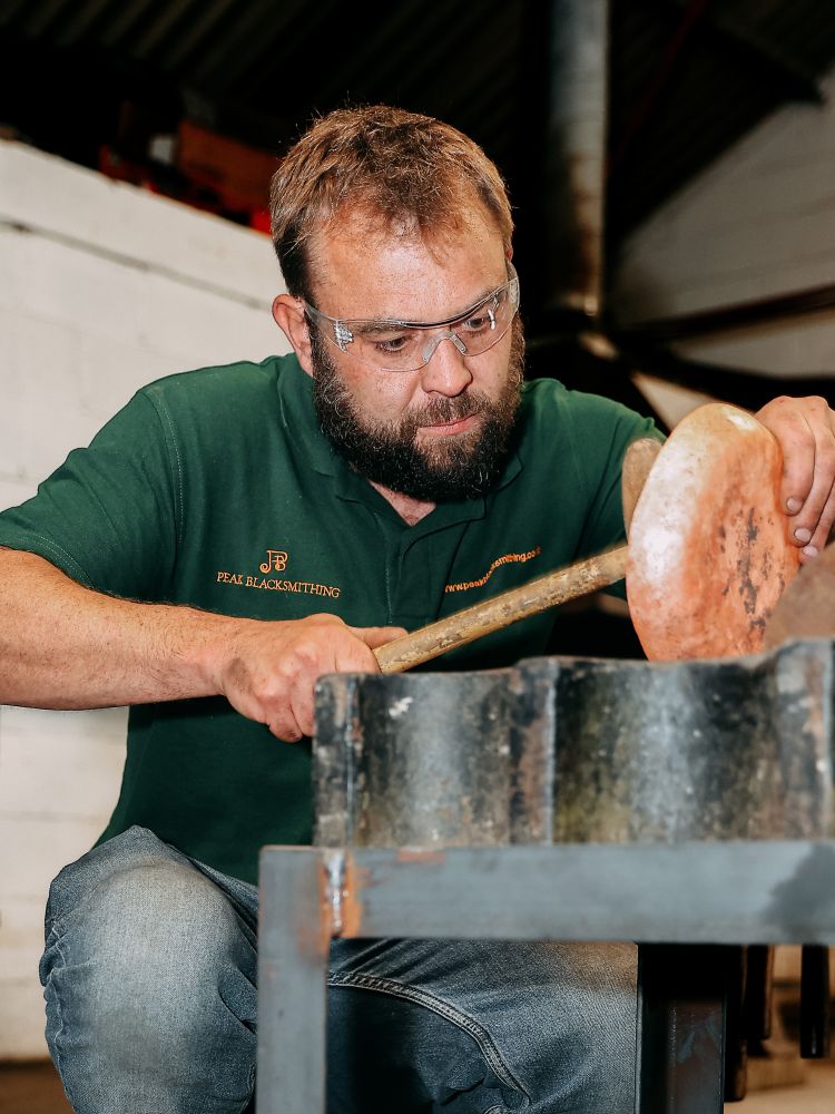 man shaping a copper bowl made on a silversmithing experience