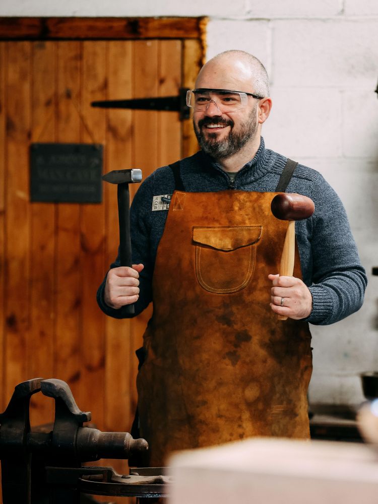 man holding two hammers while on a silversmith day course