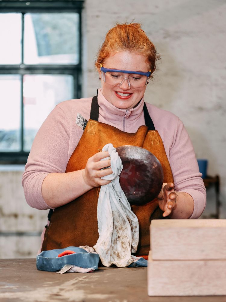 woman wiping a copper bowl made on a silversmith day course