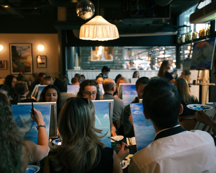 Paint and sip event with people painting a mountain scene