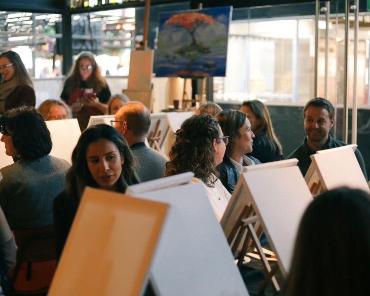People at easels ready to paint at paint and sip event
