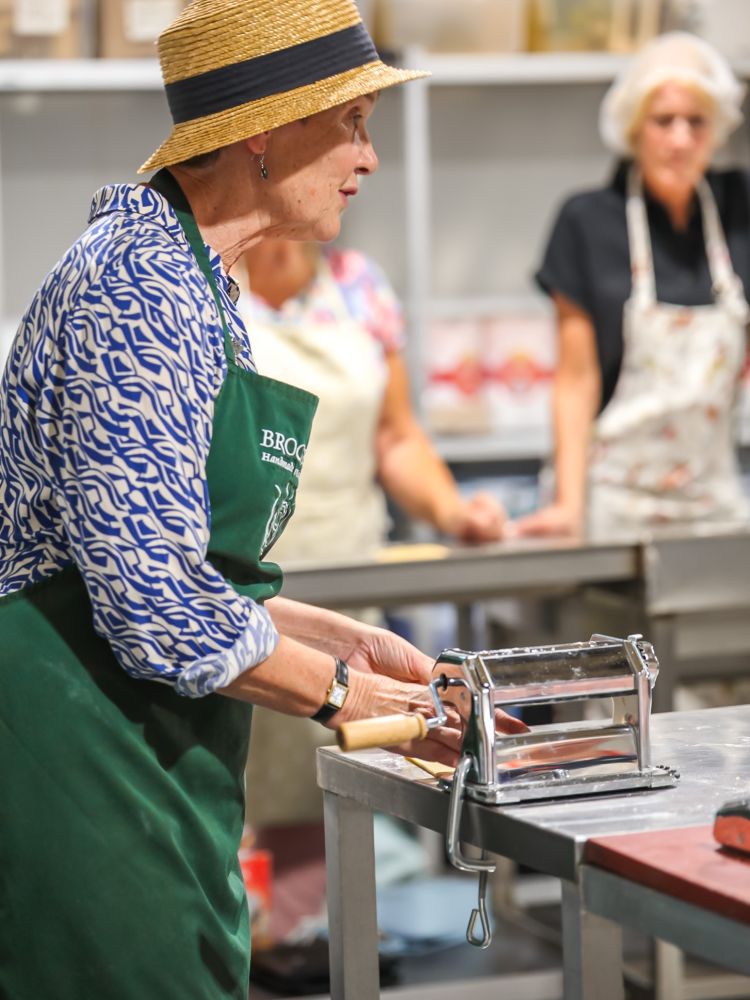 instructor demonstrating how to use a pasta machine on a pasta making workshop