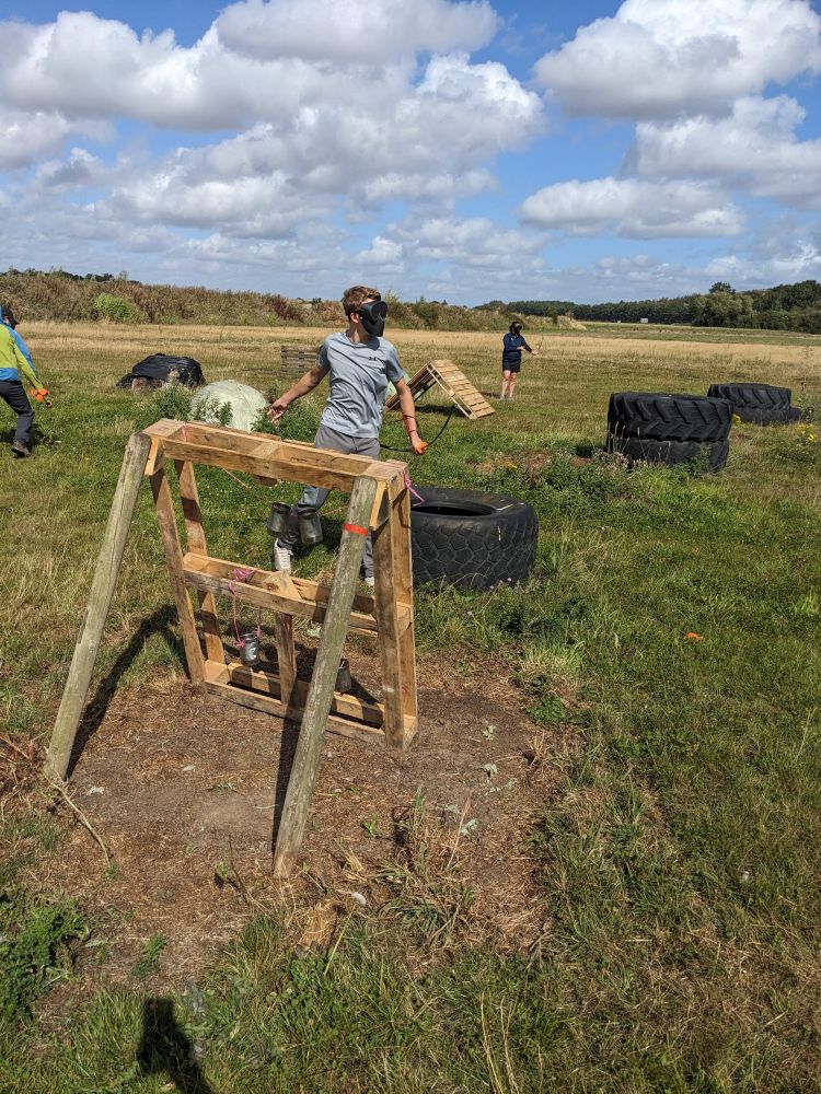 boy behind a wooden obstacle on a combat archery experience