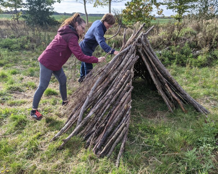 couple making a den out of sticks on a bushcraft experience
