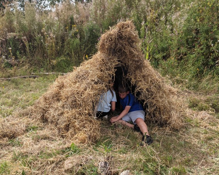 people hiding in den made on a bushcraft experience