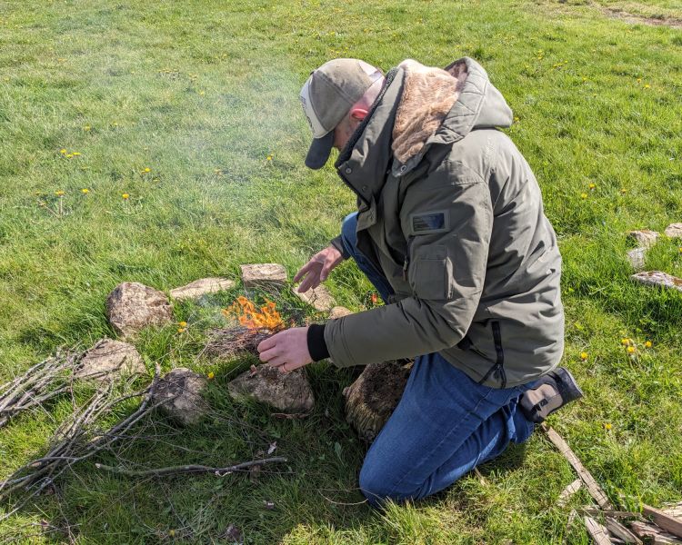 man lighting a campfire on a bushcraft experience