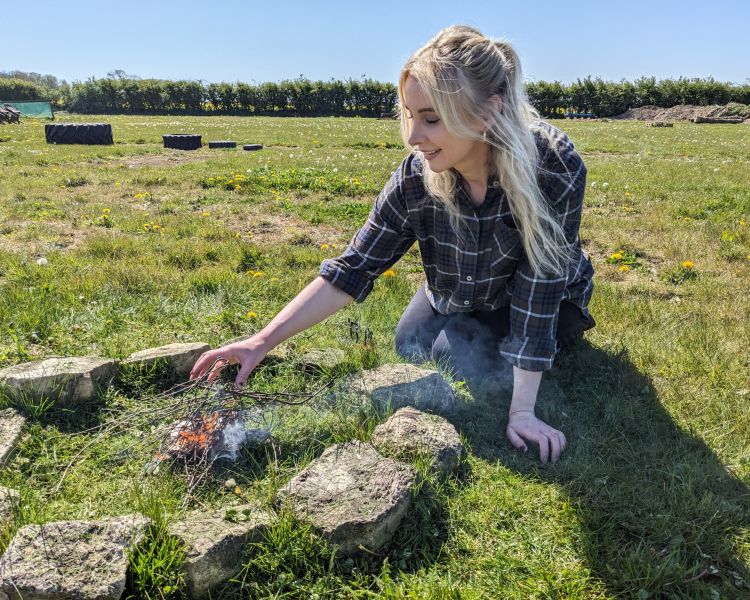 woman making a campfire on a bushcraft experience