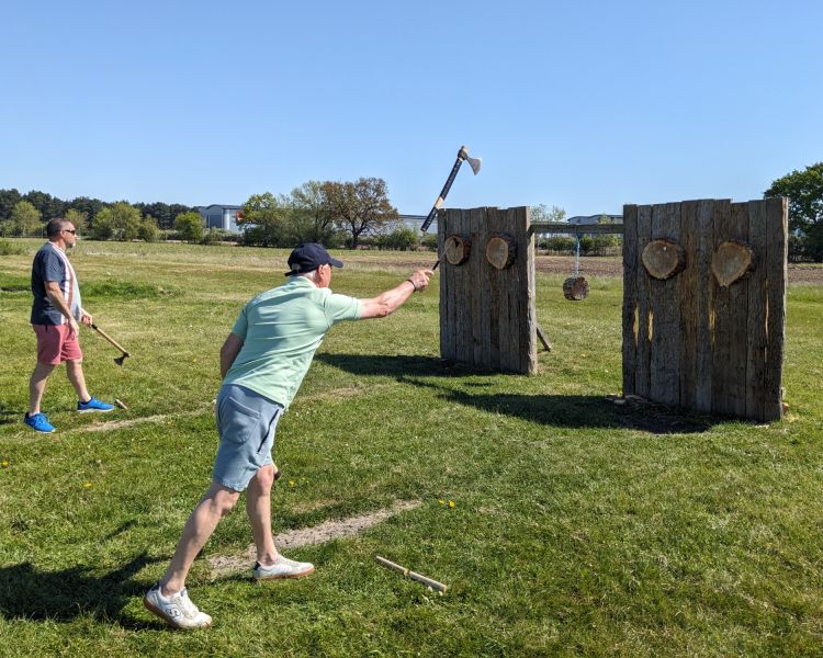 man throwing an axe at a wooden target on an axe throwing experience