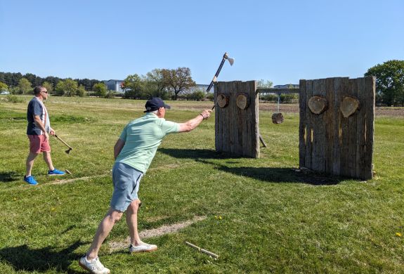 man throwing an axe at a wooden target on an axe throwing experience
