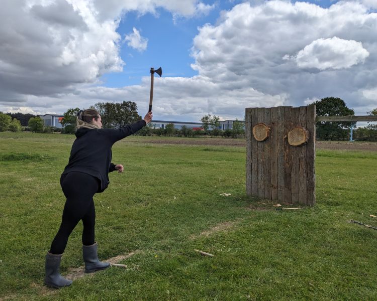 woman throwing an axe at a wooden target on an axe throwing experience