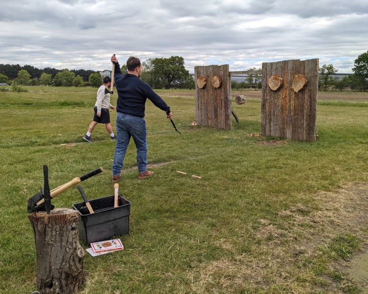 people throwing axes and knives at wooden targets