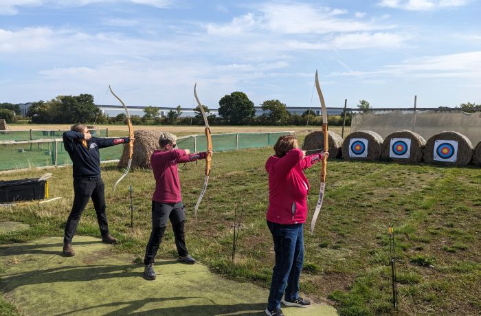 three people shooting arrows at targets on a robin hood weapons experience