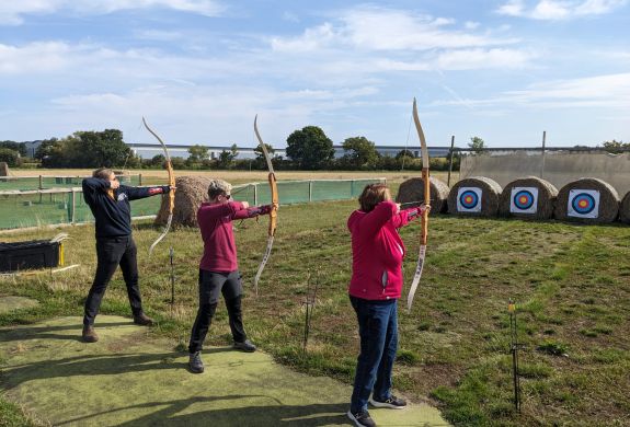 three people shooting arrows at targets on a robin hood weapons experience