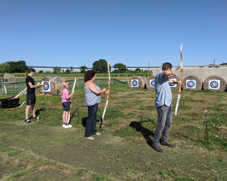 three people shooting arrows at targets on a robin hood weapons experience