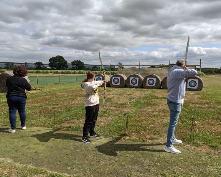 three people shooting arrows at targets on a robin hood weapons experience