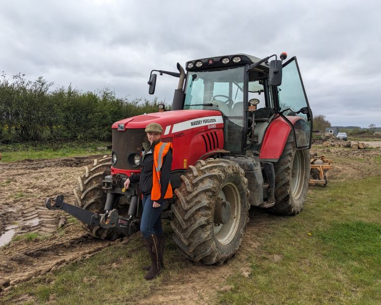 woman posing next to tractor on a tractor driving experience
