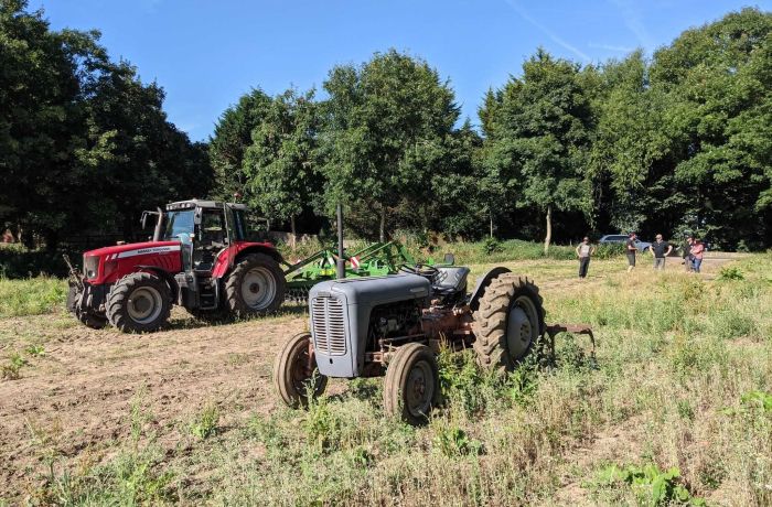 a modern and a vintage tractor in a field