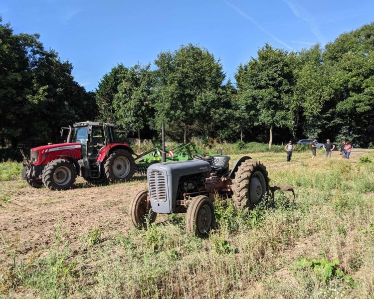 a modern and a vintage tractor in a field