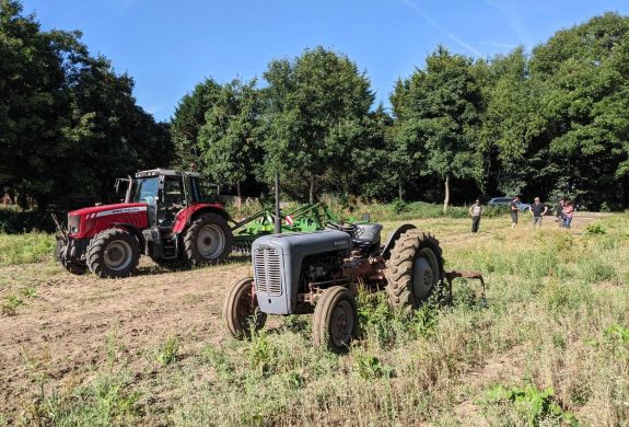 a modern and a vintage tractor in a field