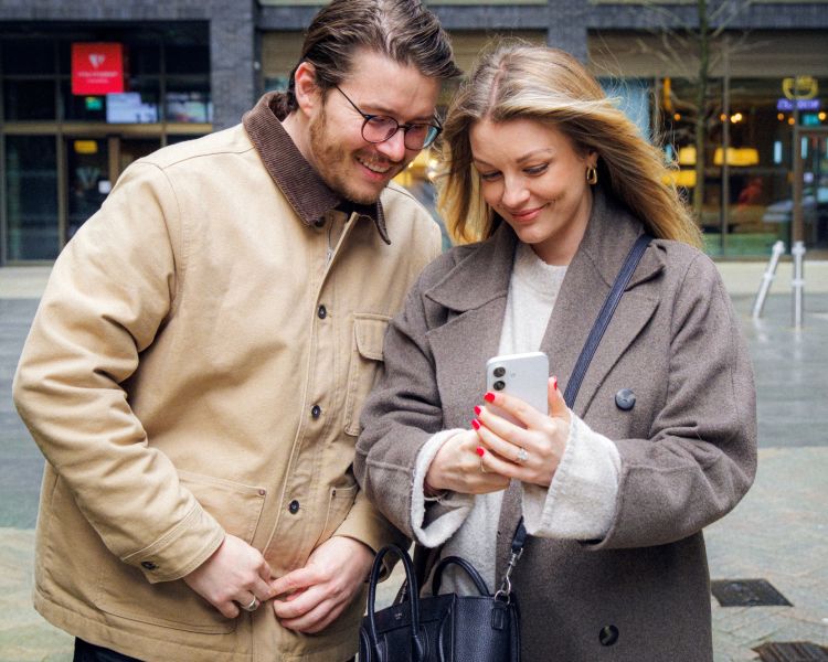 Couple looking at phone on street on food treasure hunt in manchester