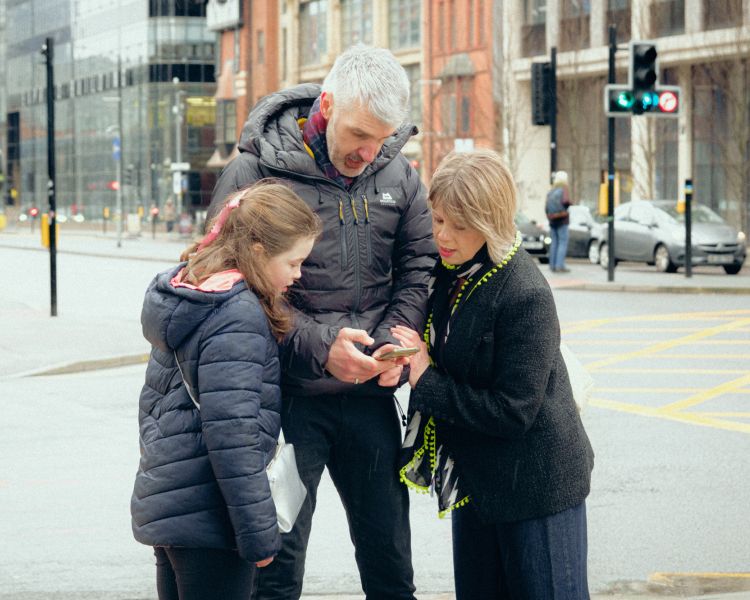 Family looking at phone on brunch treasure hunt in manchester