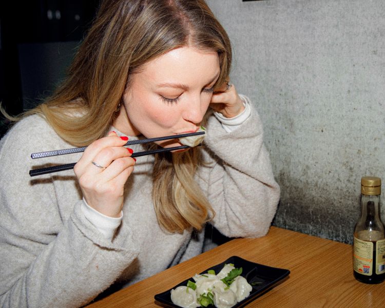 Woman eating dumpling with chopsticks on food treasure hunt in manchester