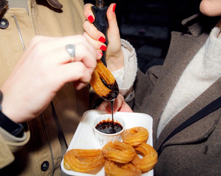 Dipping churros in chocolate sauce on a food treasure hunt in manchester