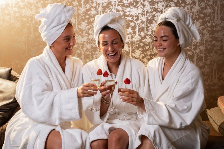 Three women in spa robes and glasses of bubbly