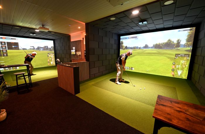 Two men on indoor golf simulators