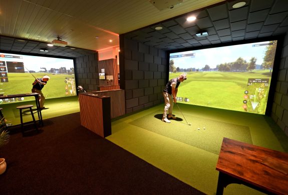 Two men on indoor golf simulators