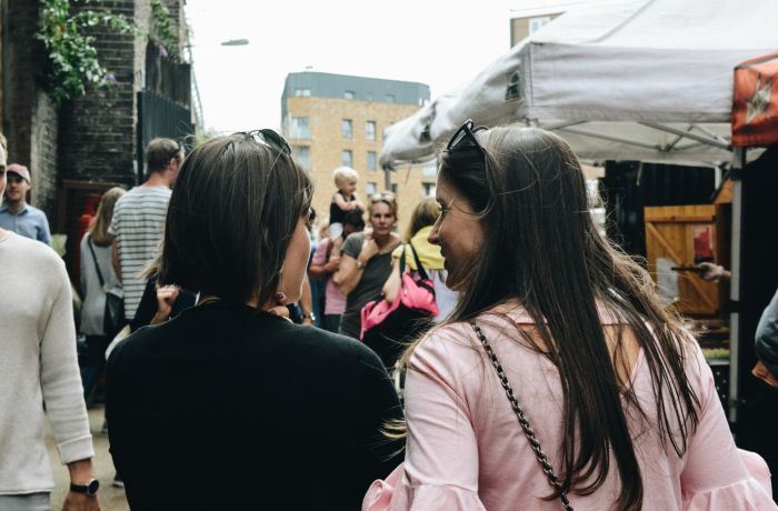 two ladies seen from behind walking down a busy street