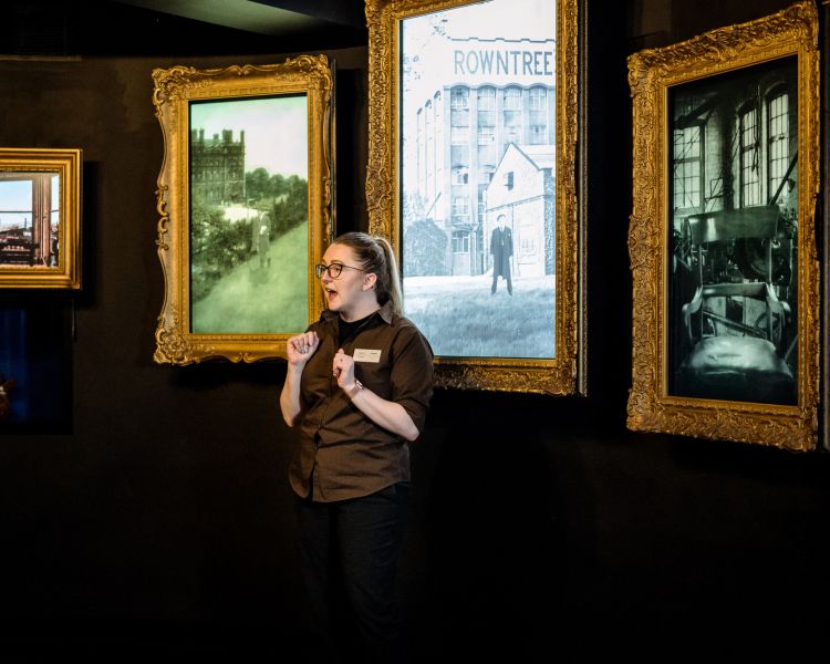 Guide standing by pictures on tour of york chocolate story
