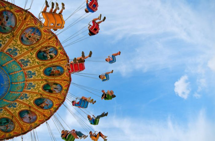 view from below looking up at people on a carousel against a blue sky