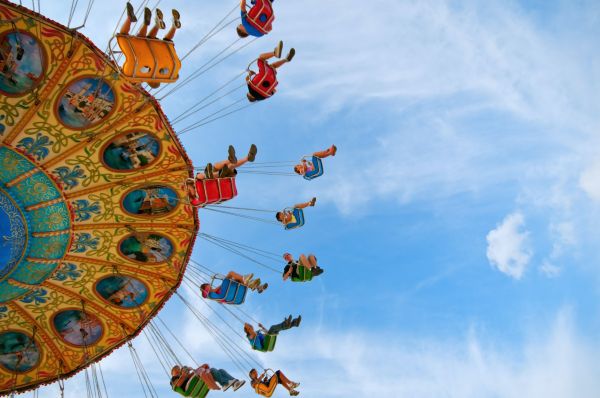 view from below looking up at people on a carousel against a blue sky