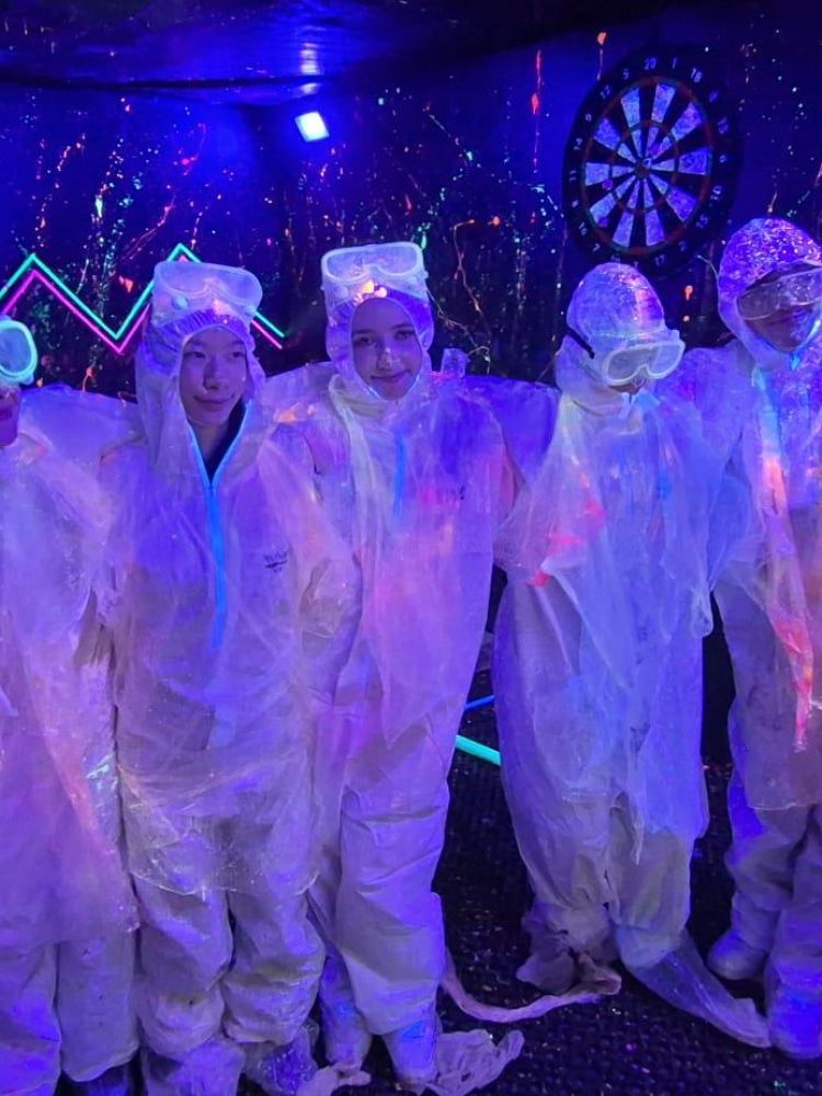 A group in paint suits in the neon splatter room