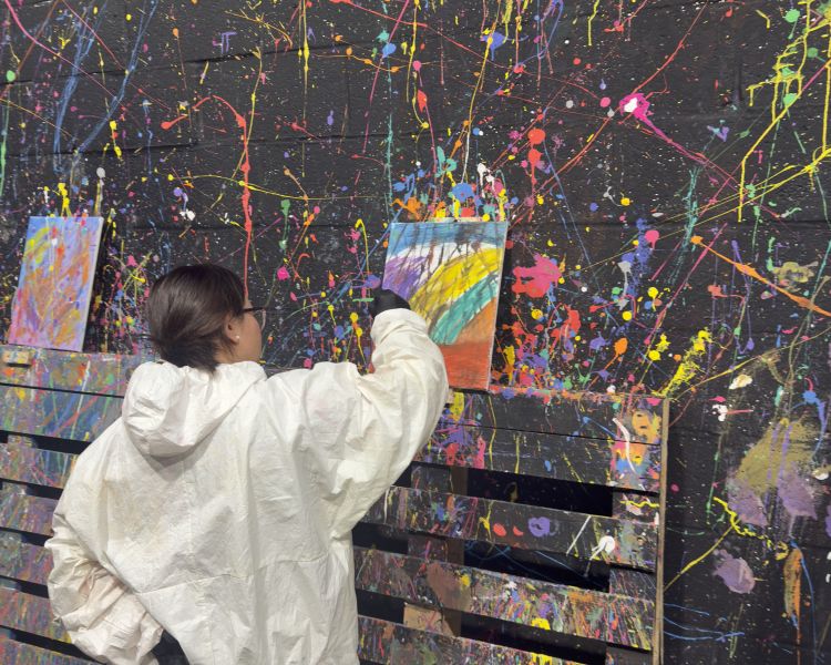 A guest spray painting a canvas