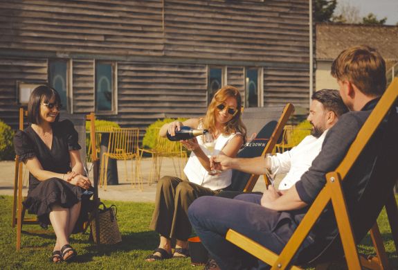 people sitting in deckchairs in sunshine drinking wine at chapel down winery