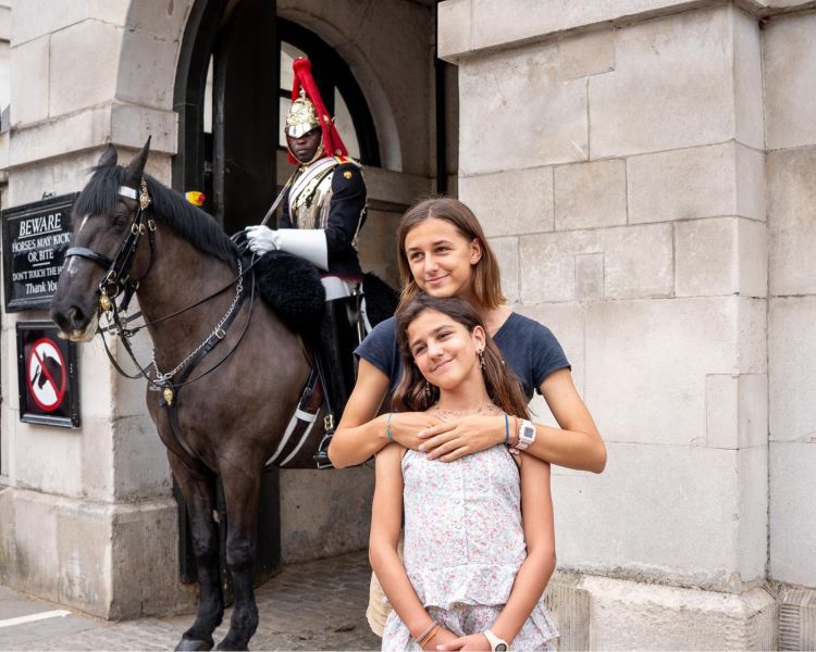Two girls having photo taken next to royal guard