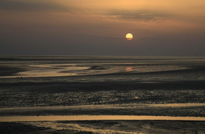 the sun setting on the coast in the wirral