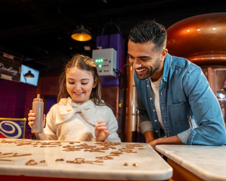 young girl with dad doing chocolate doodles at cadbury world