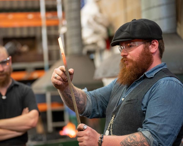 blacksmith demonstrating techniques to participants on a blacksmith experience