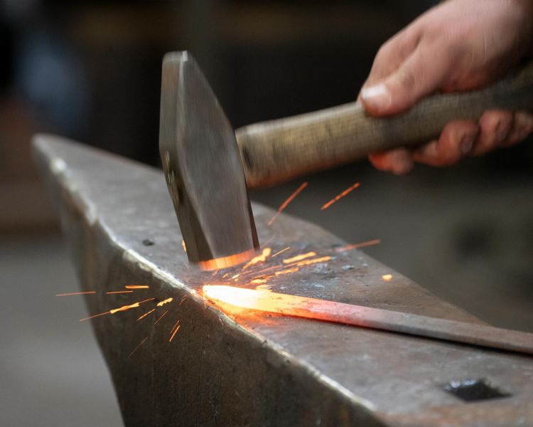 hammering a piece of hot steel on a blacksmith experience in suffolk
