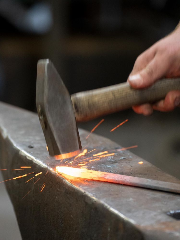 hammering a piece of hot steel on a blacksmith experience in suffolk