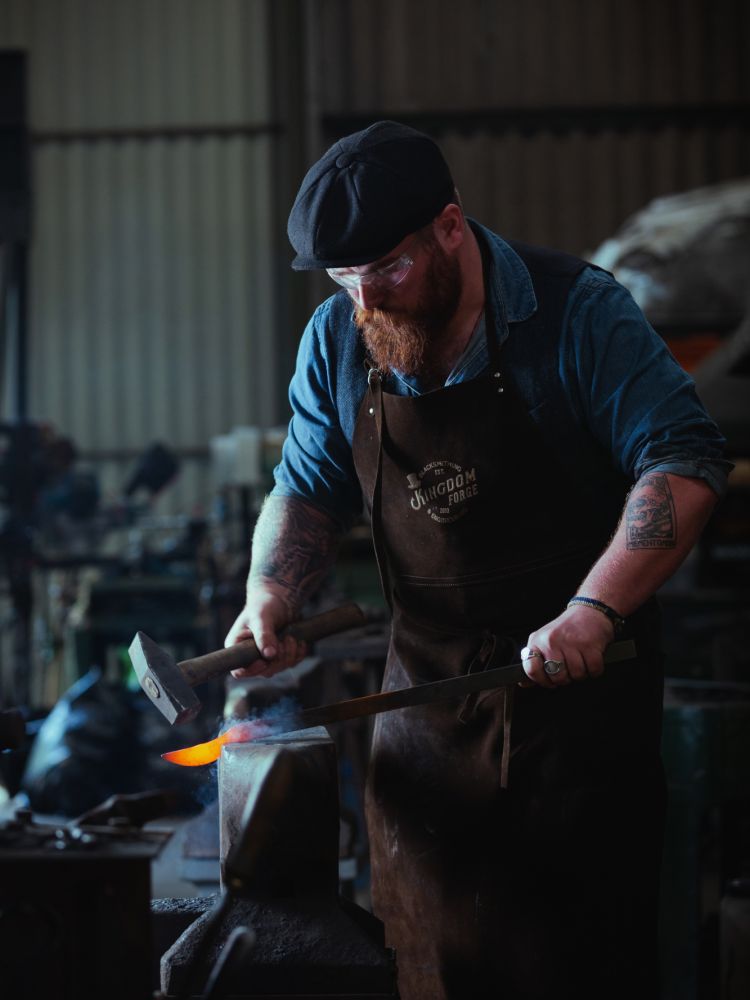 man hammering hot steel into a knife on a blacksmith experience in suffolk