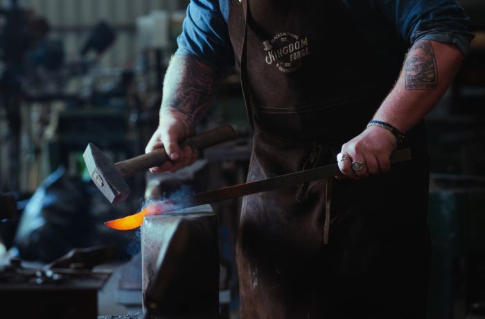 man hammering hot steel into a knife on a blacksmith experience in suffolk